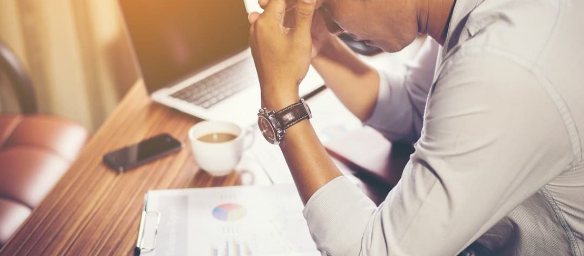 Canva - Man Holding His Head in front of Laptop